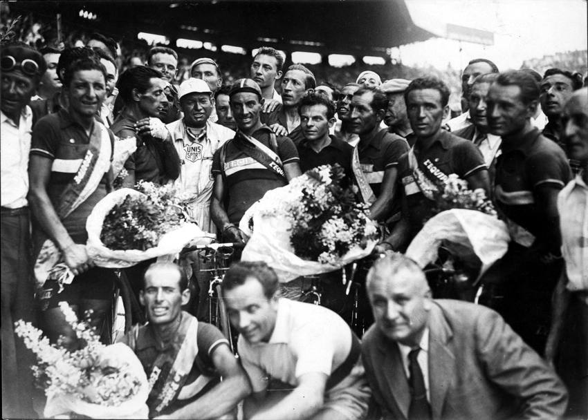 Tour de France 1949. Parigi, Parco dei Principi, i festeggiamenti della squadra italiana per la vittoria di Fausto Coppi. Il Campionissimo fu il primo a vincere Giro e Tour nello stesso anno e per ben due volte. Coppi  il secondo da sinistra, di profilo con la mano sinistra sulla spalla destra. (Presse Sports)